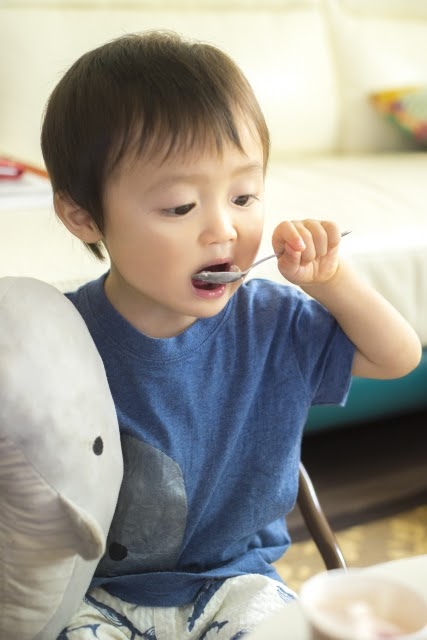 ご飯をスプーンですくって食べる子ども