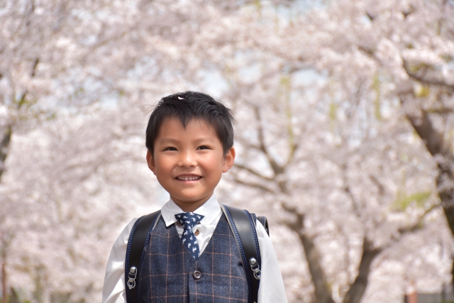 桜の咲く中、ランドセルを背負う1年生の男の子